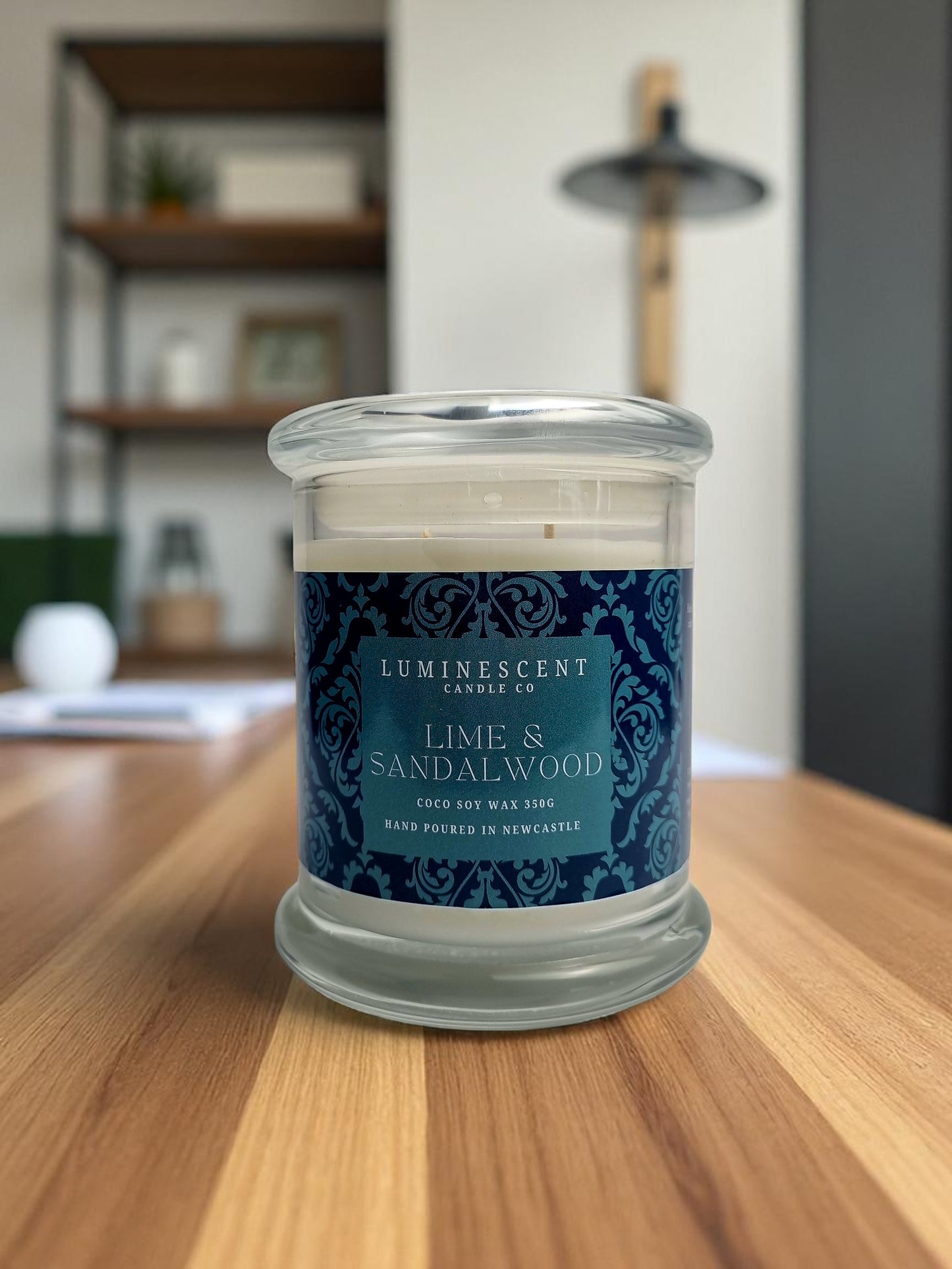 Candle with a blue label on a wooden surface, with a blurred indoor background